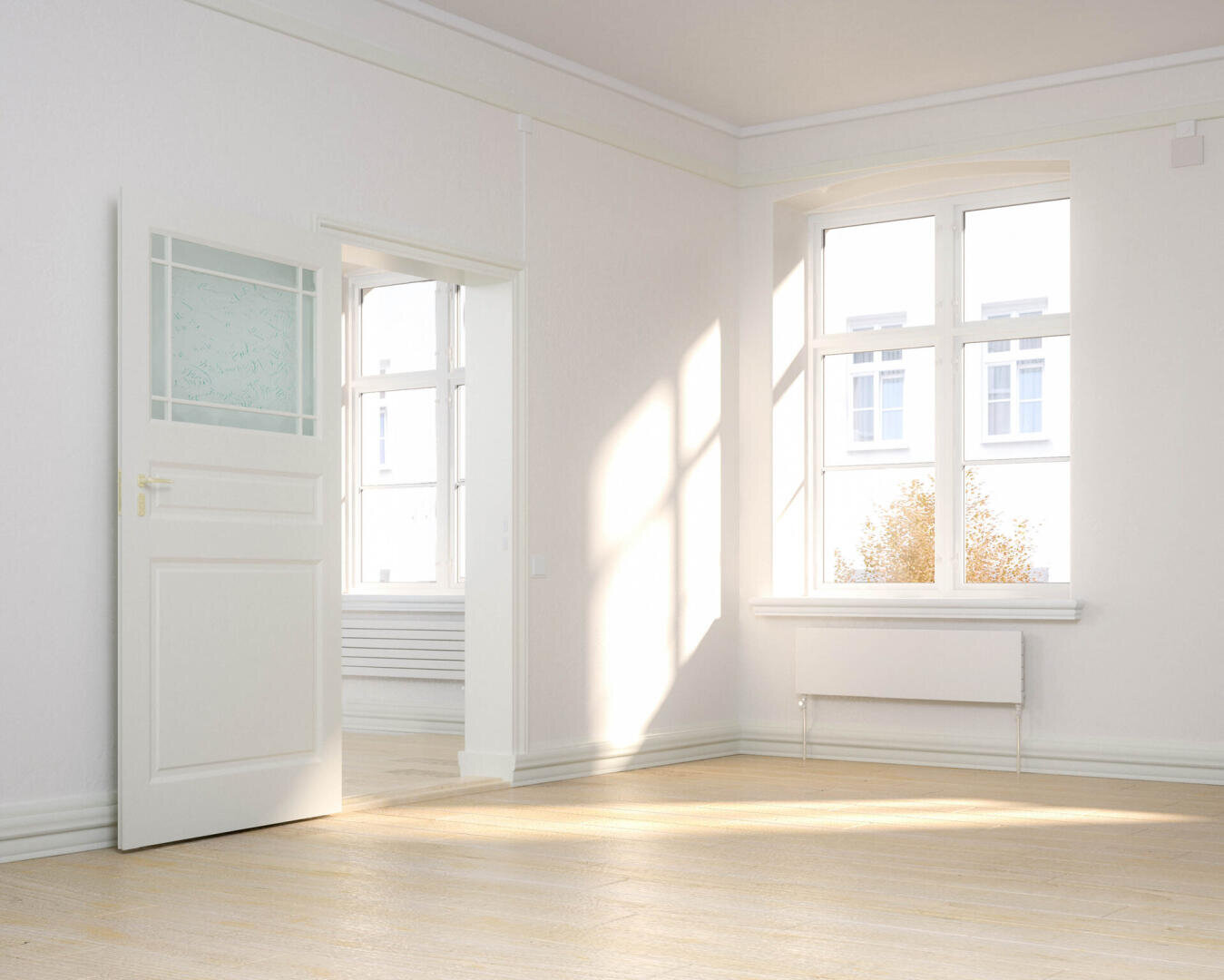 Ein heller, leerer Raum mit weißen Wänden, einer offenen weißen Tür, großen Fenstern, die Sonnenlicht hereinlassen, und hellem Holzboden. Vor den Fenstern sind Bäume und ein Teil eines Gebäudes zu sehen.