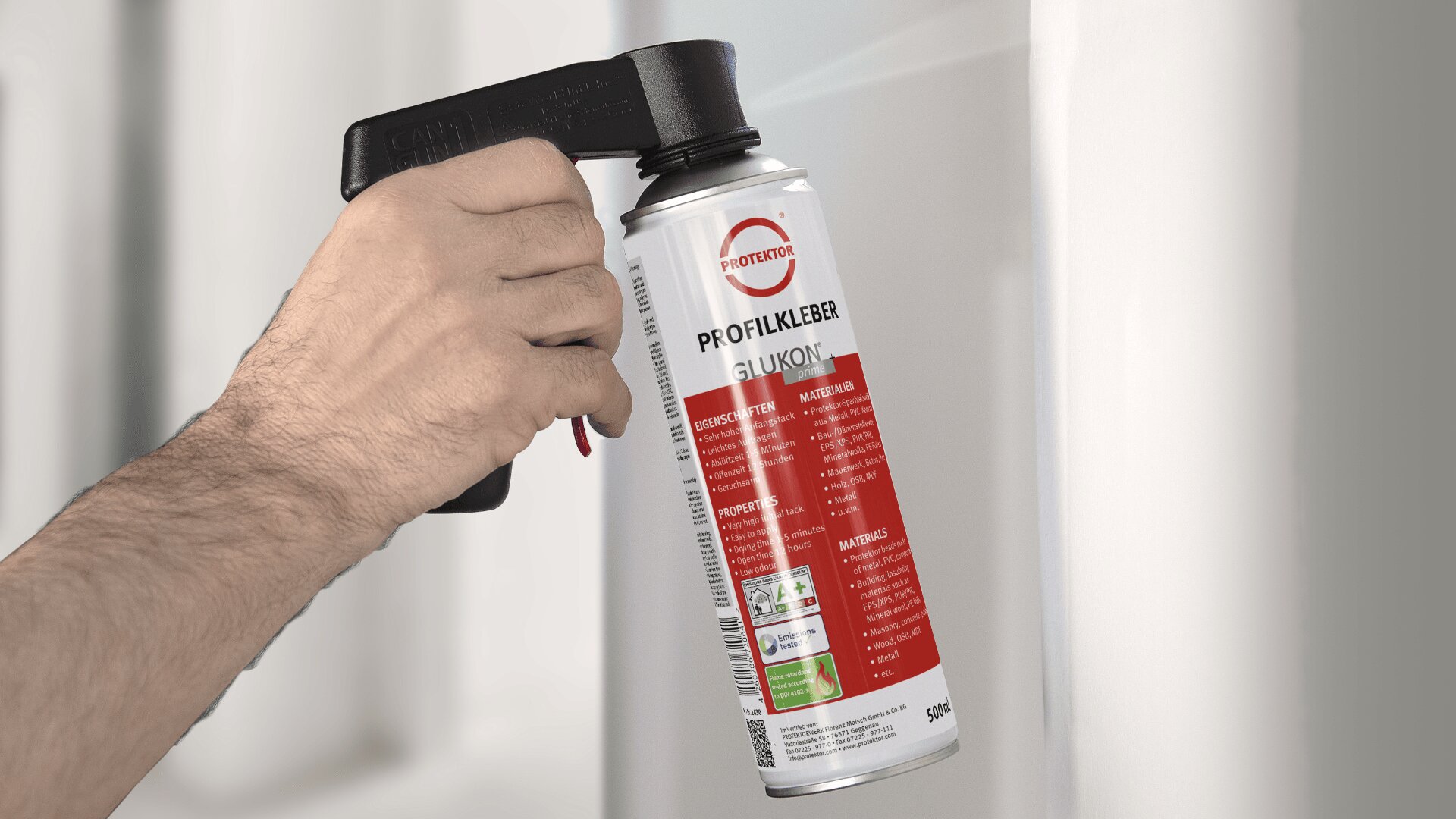 Eine Hand hält eine Sprühkleberdose mit der Aufschrift „PROFIKLEBER GLUOKYL“ und einem Sprühgriffaufsatz auf eine weiße Oberfläche. Die Dose ist mit rot-weiß-schwarzem Text und Grafiken versehen.