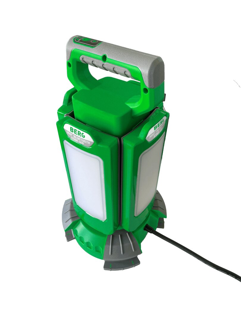Eine tragbare LED-Arbeitsleuchte in Grün und Grau mit einem Griff oben und der Aufschrift „BERG“, die aufrecht auf einem runden Sockel steht und an der ein Netzkabel angeschlossen ist.