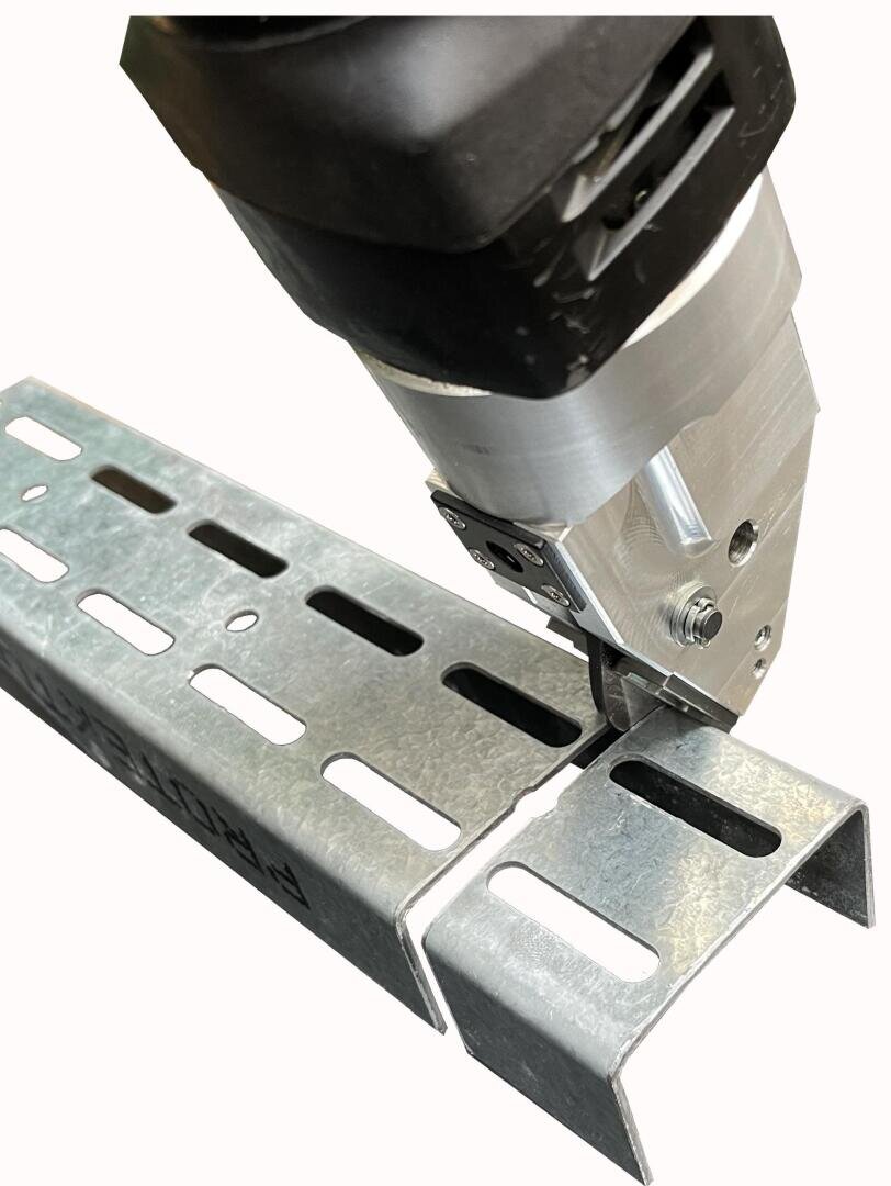 A close-up of a power tool cutting through a piece of galvanized steel channel with evenly spaced slots. The tool appears to be a metal nibbler, making a clean, precise cut along the channel.