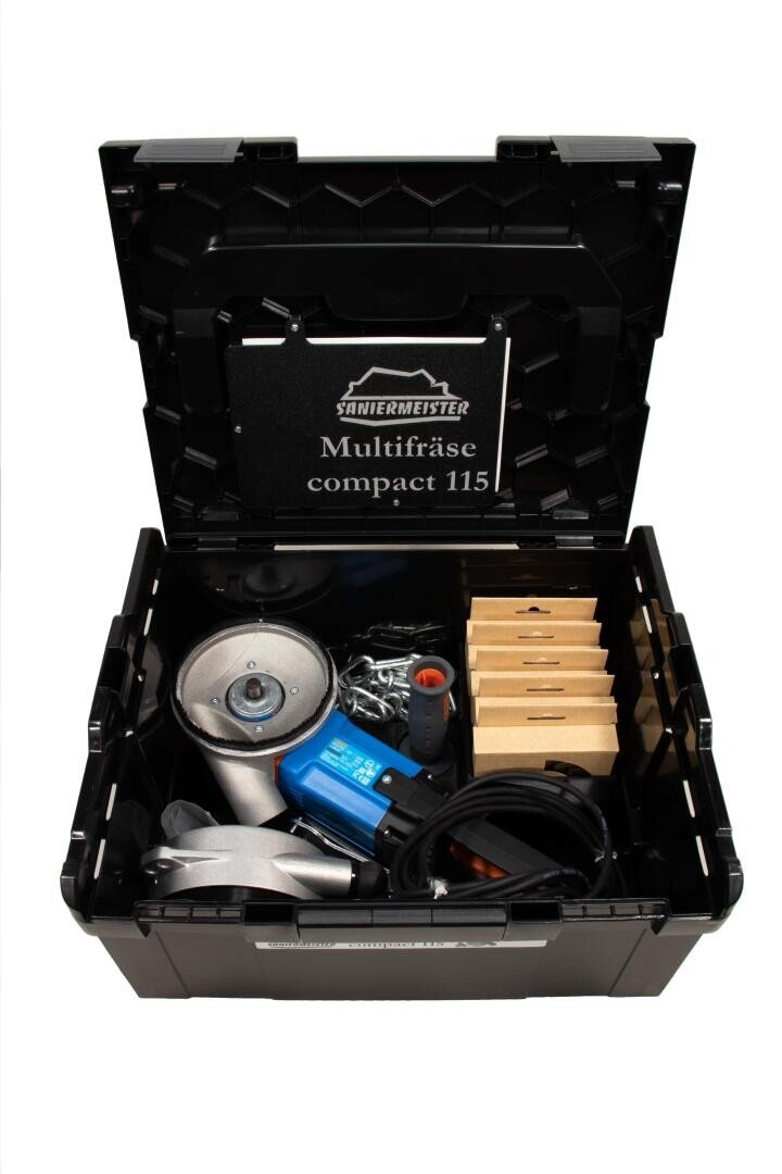 Ein offener schwarzer Werkzeugkasten mit der Aufschrift „Multifräse compact 115“ enthält ein blau-silbernes Elektrowerkzeug, einen Griff, Kabel, Gurte und mehrere gestapelte rechteckige Blöcke.
