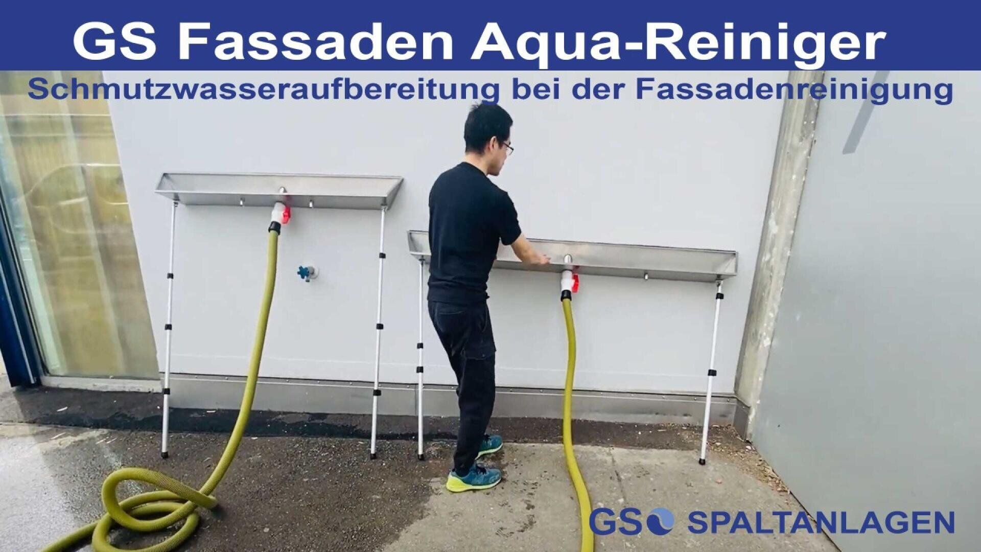 A person uses a hose to clean a metal facade at an outdoor station. Two cleaning stations are positioned against a wall, each with a yellow hose attached. German text about facade cleaning is displayed at the top of the image.