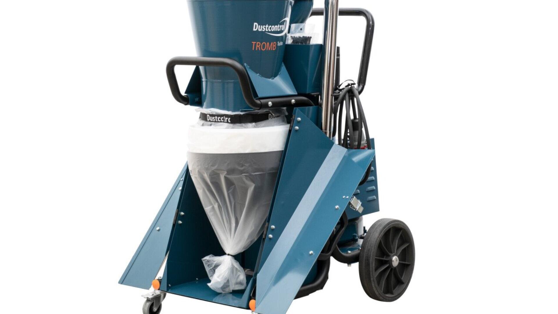 A blue industrial dust extractor on wheels with a transparent collection bag, handlebar, and attached hoses, labeled Dustcontrol Tromb.