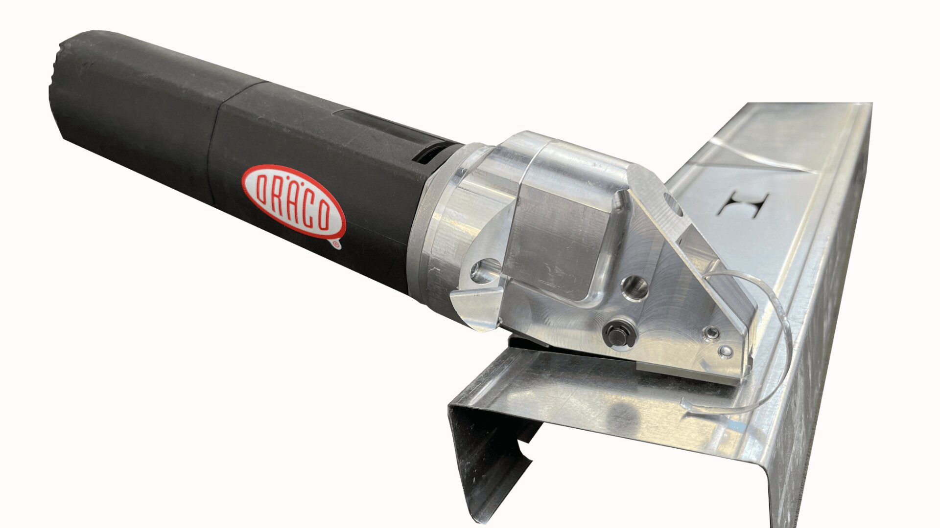 Eine Nahaufnahme einer elektrischen Blechschere der Marke DRÄCO, die ein Stück Wellblech durchschneidet, wobei das Werkzeug schräg positioniert ist.