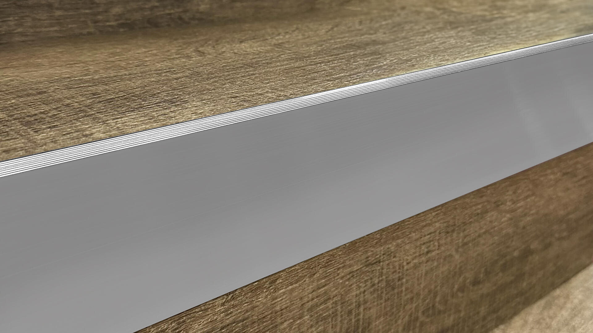 Close-up view of the edge of a wooden step with a silver metallic strip running along the front, likely for protection or traction, on a staircase with wood grain texture visible.