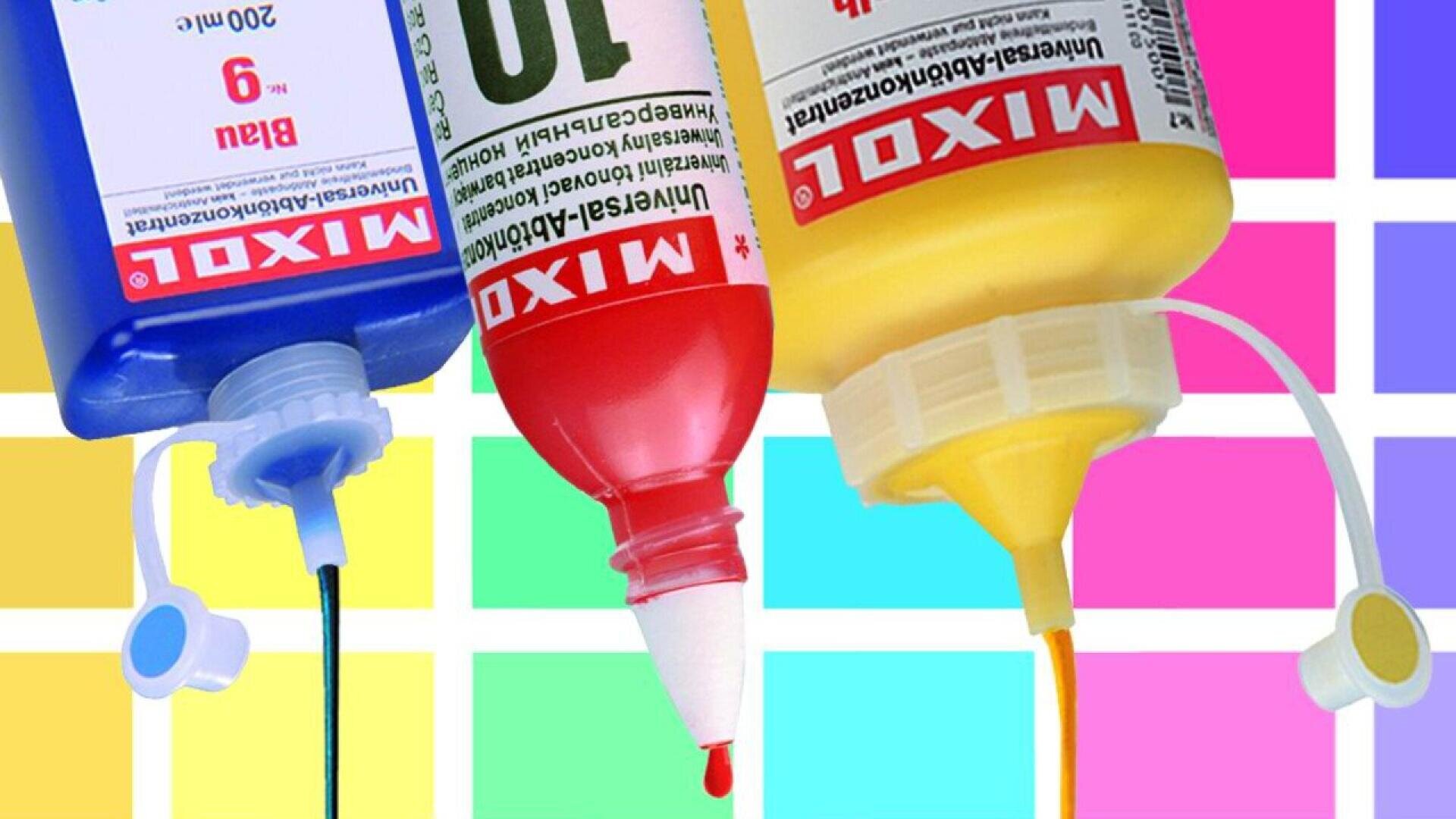 Three squeeze bottles of blue, red, and yellow ink are positioned upside down with ink dripping out, set against a colorful grid background of pastel squares.