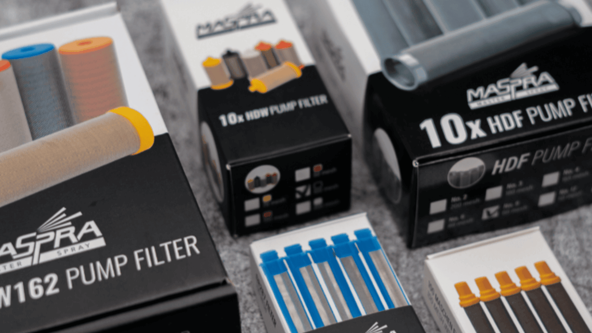 Boxes and packages of MASPRA spray pump filters and related products are displayed on a surface, showing various types, quantities, and package designs in black, white, and blue colors.