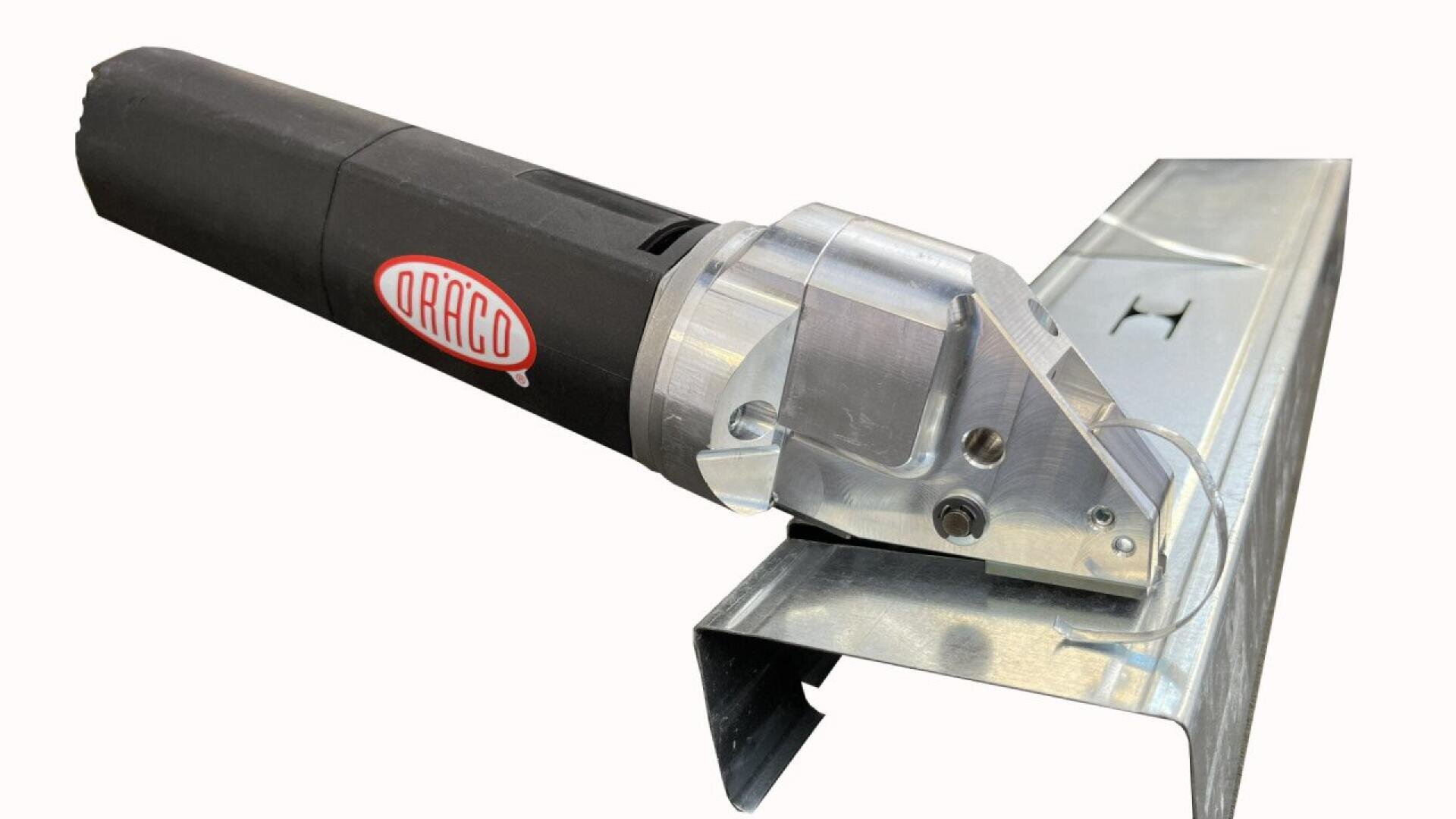 A black and silver electric metal shear tool, branded DRÄCO, is cutting through a piece of galvanized sheet metal with a bent edge.