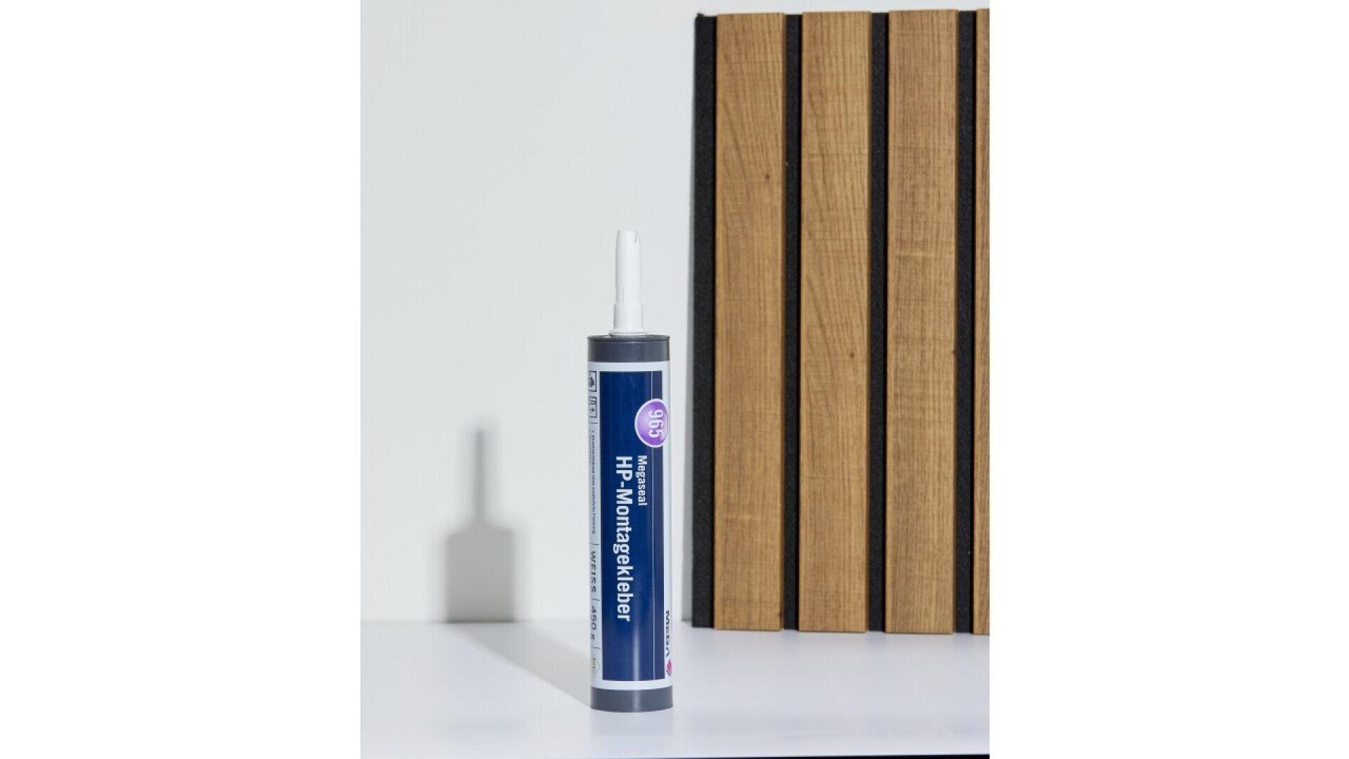 A tube of adhesive labeled HP Montagekleber stands upright on a white surface next to a vertical wooden panel with black gaps between the slats.